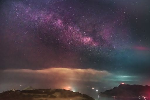 A low angle shot of the breathtaking starry sky over the mountains and the water