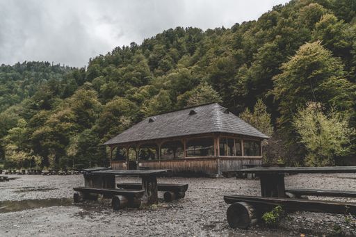 An old abandoned wooden alcove and tables in the forest mountains on a gloomy day