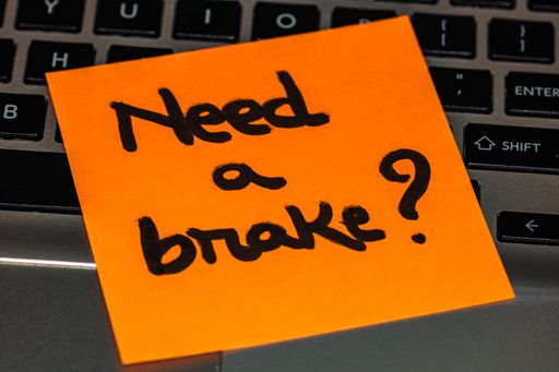 A closeup shot of a "Need or brake?" orange sticky note on a computer keyboard; business concept