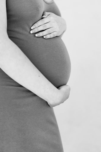 A beautiful vertical shot of a pregnant woman holding her belly; 27 weeks