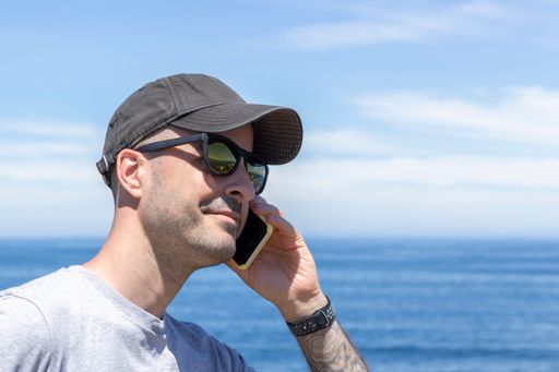 A Spanish male talking on his mobile phone from the beach, during his summer vacation.