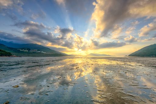 A low angle shot of the ocean under the breathtaking lights and clouds in the blue sky