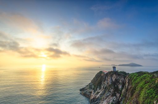 A high angle shot of a lighthouse on a cliff by the beautiful ocean captured at sunset in Hong Kong