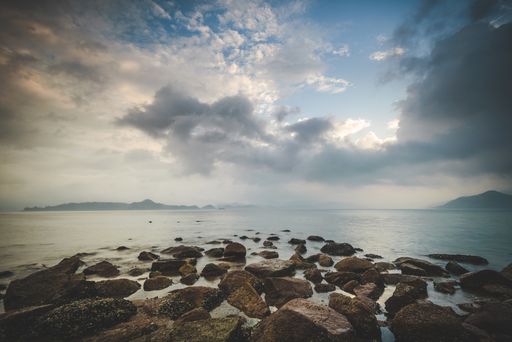 A low angle shot of the rocky shore by the sea under the beautiful cloudy sky