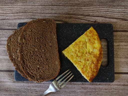 A top view of an omelet and bread slices on a cutting board.
