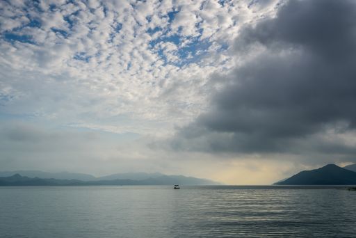 A low angle shot of the breathtaking cloudy sky over the calm and beautiful ocean