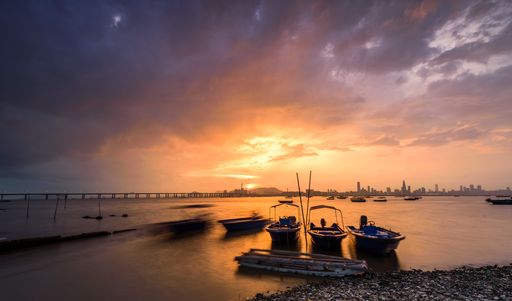 The motorboats parked on the water by the water with sunset and a city visible in the background
