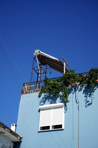 A low-angle shot of a building with windows and shutters against the blue sky