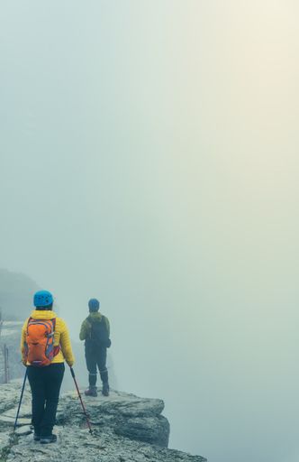A couple of hikers standing on the mountains under a foggy sky