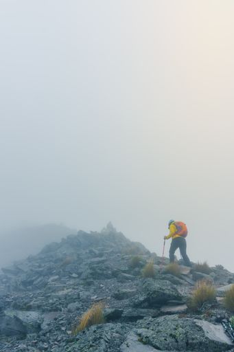 A vertical shot of a hiker climbing on the mountains