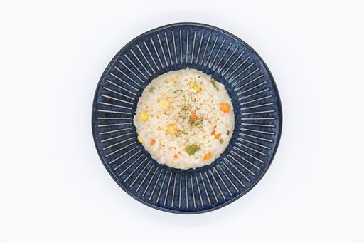 A top view of a bowl of rice with carrots, pepper, and corn isolated on a white background