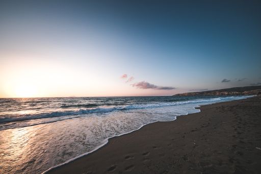 A serene view of the foamy waves of the ocean washing the beautiful sandy beach at dawn