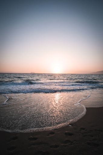 A serene view of the foamy waves of the ocean washing the beautiful sandy beach at dawn