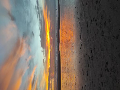A scenic view of a sandy beach at low tide during a beautiful sunset