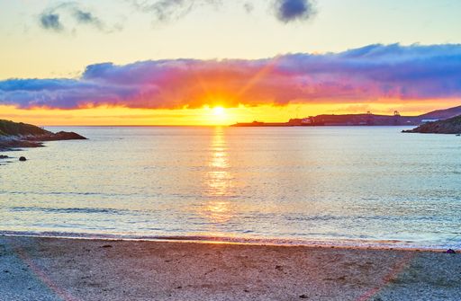 A mesmerizing view of multicolor sunset on the sea from the sandy beach at golden hour