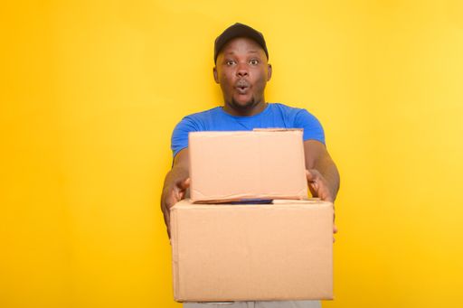 An African delivery or dispatch man carrying boxes and wearing a face cap