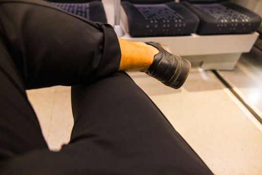 A closeup shot of a male sitting with crossed legs in a train