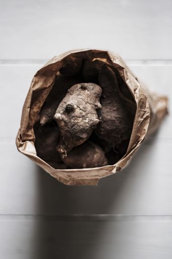 A top view of Jerusalem artichokes in a brown bag with a blurred background
