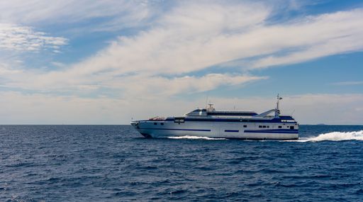 A ferry sails across the ocean under a partly cloudy sky, showcasing maritime travel and transportation.