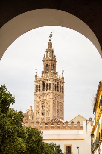 A vertical shot of Giralda bell tower unfolding behind the arch, Seville, Spain.