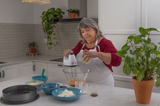 older woman with white hair making a strawberry cake in her home kitchen