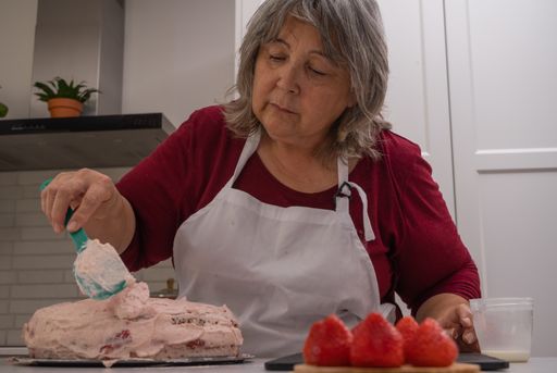 older woman with white hair making a strawberry cake in her home kitchen