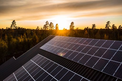 Aerial view of a house with roof solar cells, sunset forest background - tilt, drone shot