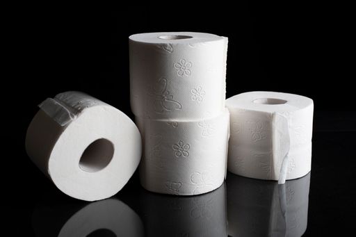 A closeup of white toilet paper rolls isolated on a black background