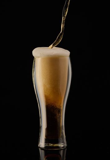 A vertical shot of a glass of juice on a black background