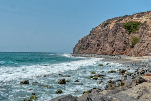 A beautiful shot of the sea with high cliffs on the side under a clear blue sky
