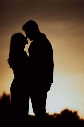 A silhouette shot of a romantic couple having an intimate moment on a beautiful da