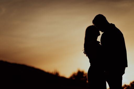 A silhouette shot of a romantic couple having an intimate moment on a beautiful day