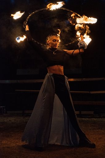 A young Romanian woman playing with fire in the dark during a medieval festival in Ardud