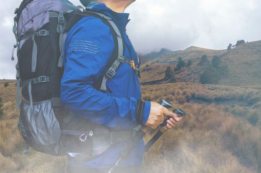 A backpacker with trekking poles hiking the mountains on a cloudy day