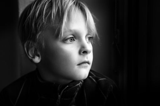 A grayscale shot of a Caucasian boy with big deep eyes on a black background