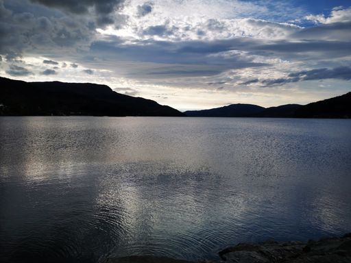 A shot of a lake with a reflection under stormy sky with mountains in the background