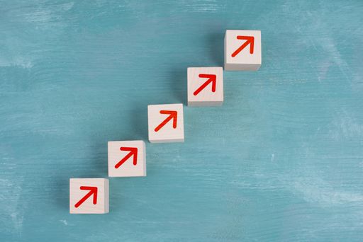 Red arrows going up on wooden cubes, blue background