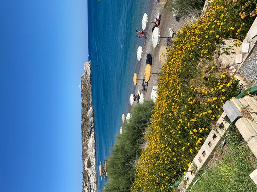 A vertical shot of umbrellas on the beach surrounded by the sea on a sunny day