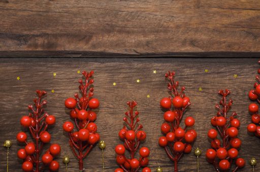 A closeup shot of red Christmas berries on a wooden surface
