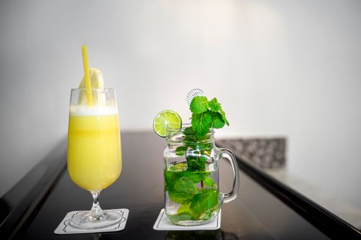 A glass of pineapple smoothie and mojito on the table