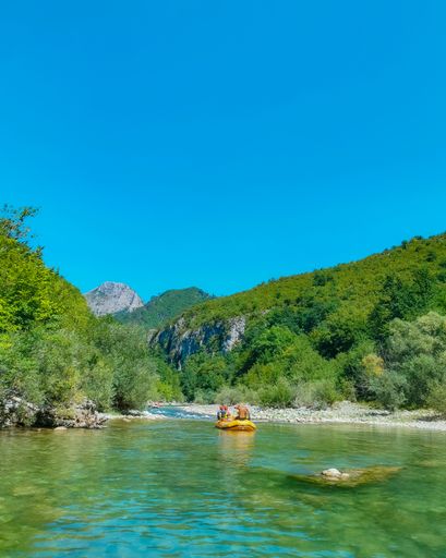 A beautiful shot of a boat full of people under a mountain covered in green