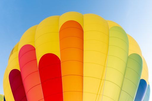 A low angle shot of a brightly painted hot air balloon detail with blue sky in the background