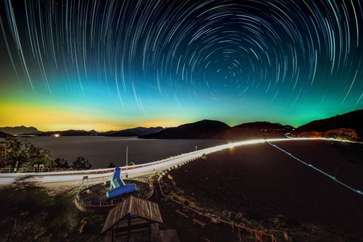 The lake surrounded by hills under a starry sky with long exposure in the night