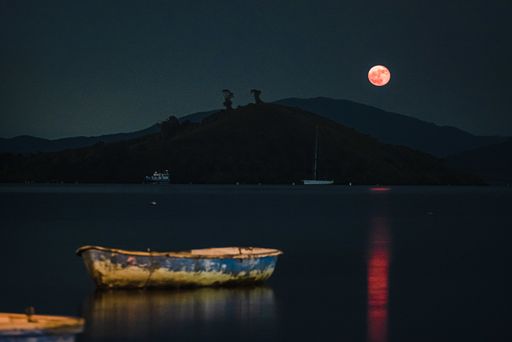 An old rusty wooden fishing boat in the lake at night