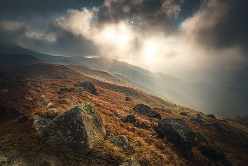 A high angle shot of the mossy stones in the mountain under the cloudy sunset sky