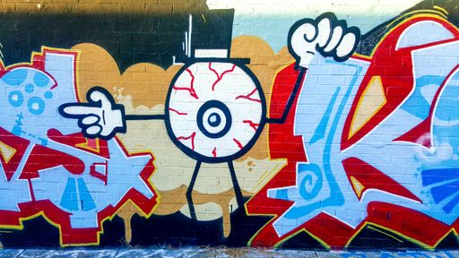 An eyeball in Top Hat: Colourful Street Art Grafitti Wall Mural in Newtown Suburb Laneway, Sydney, Australia