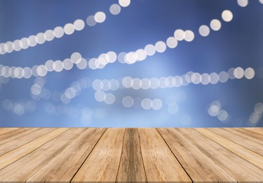 An empty wooden table with festive bokeh lights on blue background for copy space