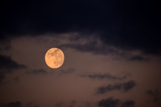 A beautiful shot of the full moon in the cloudy skies during the night