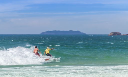 A shot of surfers riding waves at Praia do Mocambique in Florianopolis, Brazil