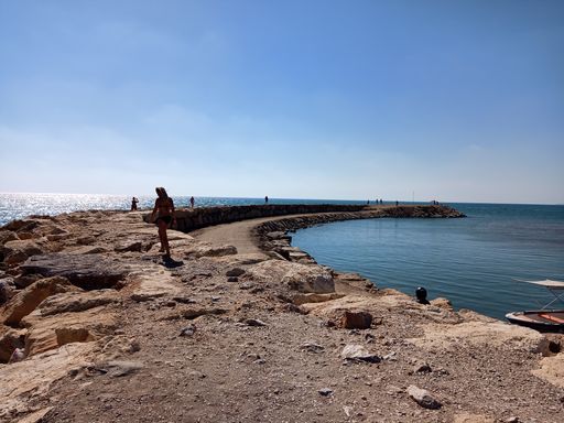 A beautiful view of the sandy rocky beach with the sea gleaming under the blue sky